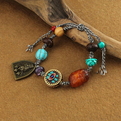 Tibetan Zakiram Turquoise Lotus Rope Bracelet – angled view with turquoise lotus bead and brass pendant on driftwood, Protection