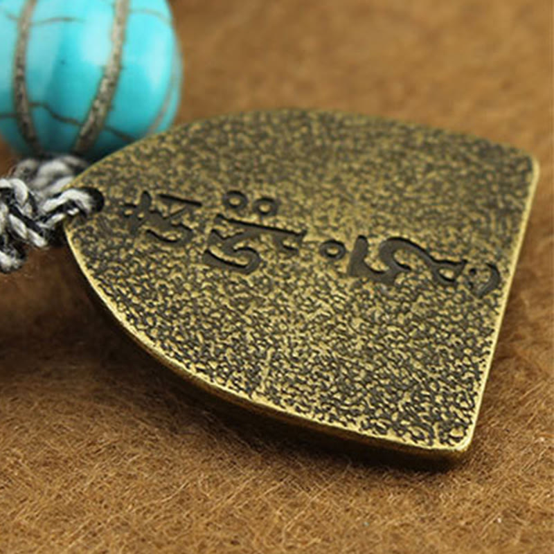 Tibetan Zakiram Turquoise Lotus Rope Bracelet – macro of shield charm with Tibetan script and turquoise accent, Turquoise