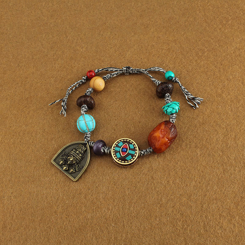 Tibetan Zakiram Turquoise Lotus Rope Bracelet – flat-lay cord bracelet with evil eye inlay and deity shield charm, Tibetan