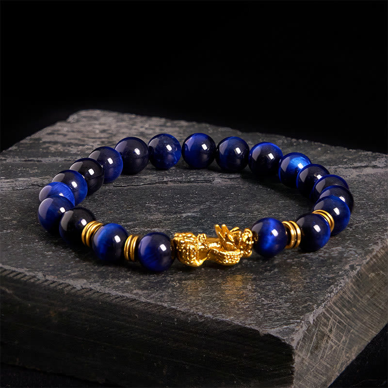 Multi-Color Tiger Eye PiXiu bracelet – blue tiger eye beads with gold charm on dark stone, feng shui wealth