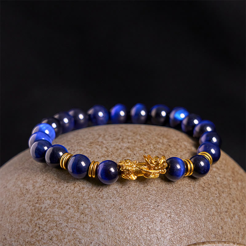 Blue Tiger Eye Pixiu Bracelet – on beige stone close-up gold Pixiu detail, tiger eye bracelet