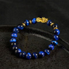 Blue Tiger Eye Pixiu Bracelet – on dark stone surface with deep blue beads, protection energy