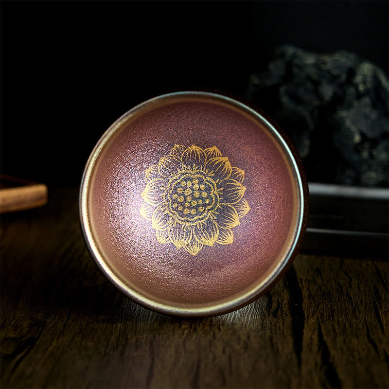 Jianzhan Golden Lotus Tea Cup – copper-bronze glaze with gold lotus on dark wood, handmade ceramic