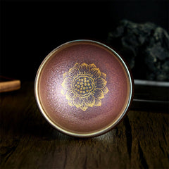 Jianzhan Golden Lotus Tea Cup – copper-bronze glaze with gold lotus on dark wood, handmade ceramic