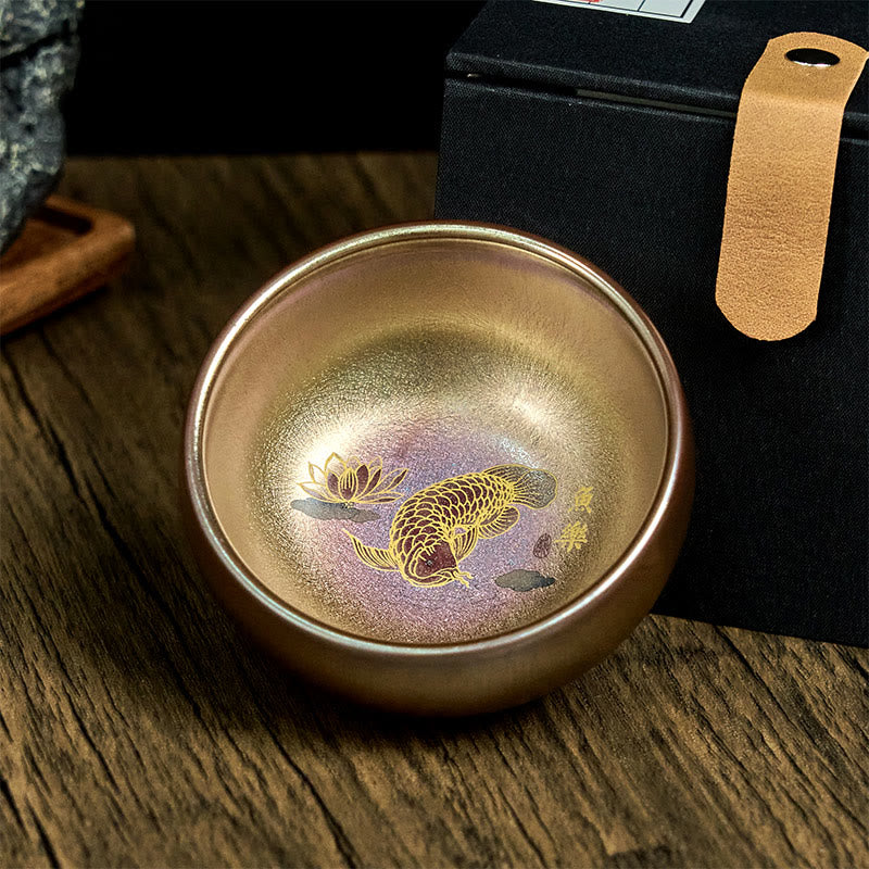 Jianzhan Koi Fish Lotus Teacup – iridescent bronze-purple glaze, gold koi and lotus, dark wood with gift box, angled view