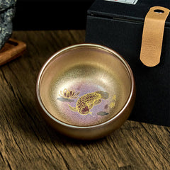 Jianzhan Koi Fish Lotus Teacup – iridescent bronze-purple glaze, gold koi and lotus, dark wood with gift box, angled view