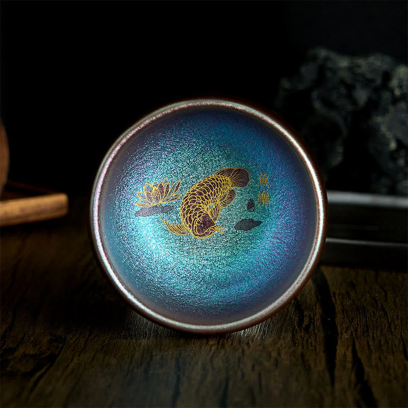Jianzhan Koi Fish Lotus Teacup – interior detail close-up, gold koi fish and lotus, iridescent purple-bronze glaze, macro