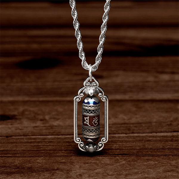 Om Mani Padme Hum Prayer Wheel Pendant – Dramatic lighting on ornate silver frame with blue lapis caps and mantra cylinder...