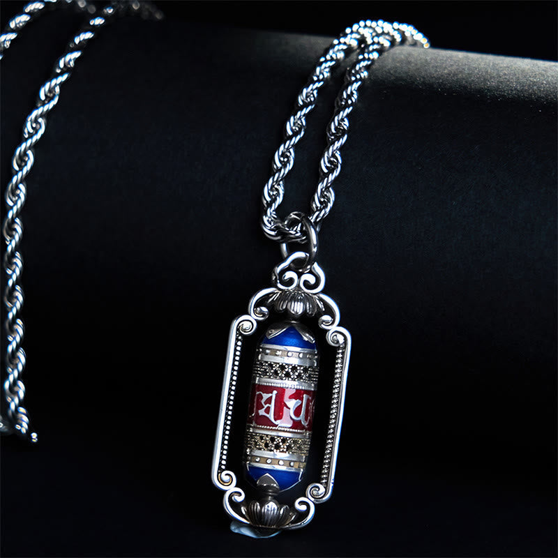 Om Mani Padme Hum Prayer Wheel Pendant – Angled on warm wood surface, revealing twisted rope chain and colored enamel barr...