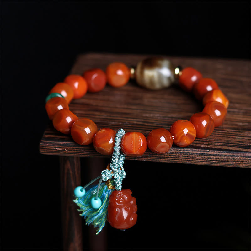 South Red Agate Dzi Bead PiXiu Bracelet – close-up on dark wood with PiXiu charm, feng shui wealth luck