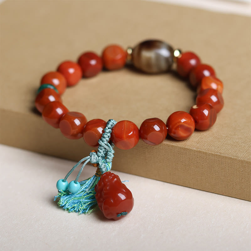 South Red Agate Dzi Bead PiXiu Bracelet – side angle on beige box with tassel, red agate good luck