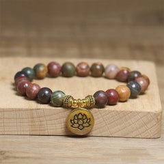 Emperor stone beaded bracelet with gold lotus charm on wood display