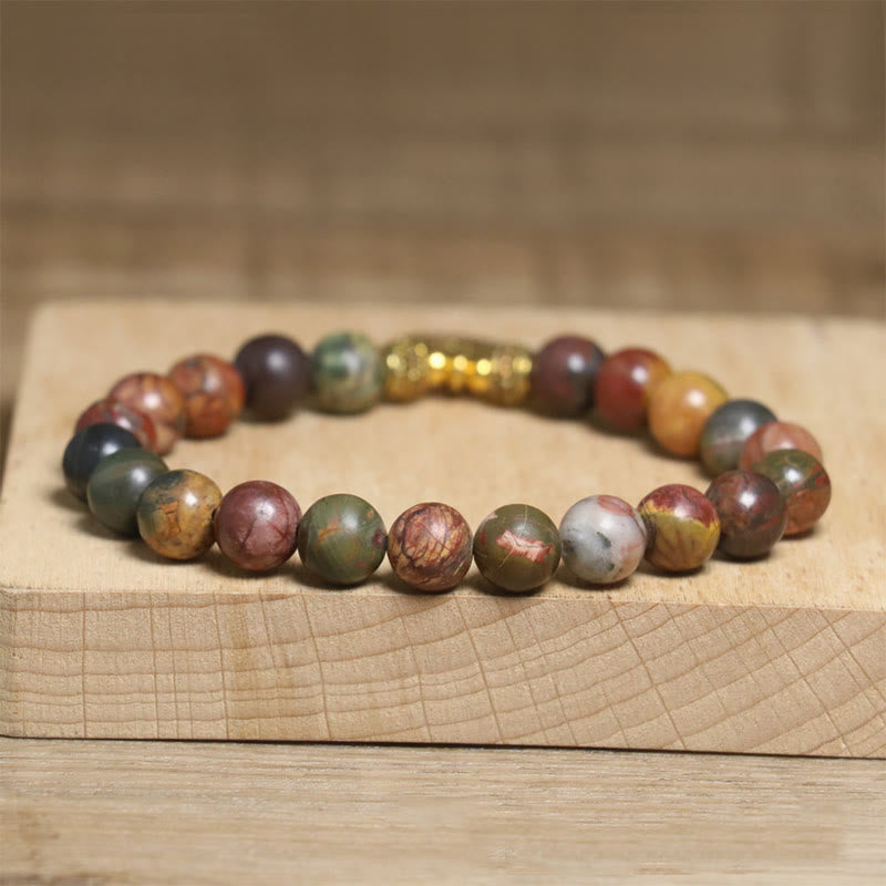 Picasso jasper stretch bracelet with gold accent bead on wood stand
