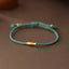 Copper Lucky Koi Fish Rope Bracelet – teal braided cord with gold koi charm on wood, luck jewelry