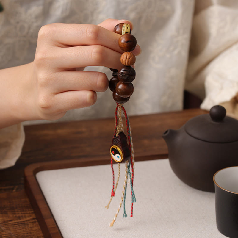 Tibet Jujube Wood Yin Yang Bracelet – hand holding bracelet beside Chinese teapot and tea cup, traditional zen lifestyle shot