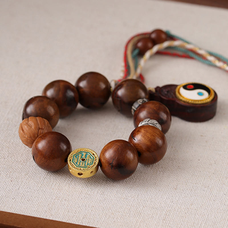 Tibet Jujube Wood Yin Yang Bracelet – close-up on linen showing dark wood beads, gold turquoise enamel accent bead and yin...