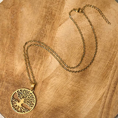 Tree of Life Titanium Steel Necklace – gold necklace flat lay on light wood showing full chain, overhead
