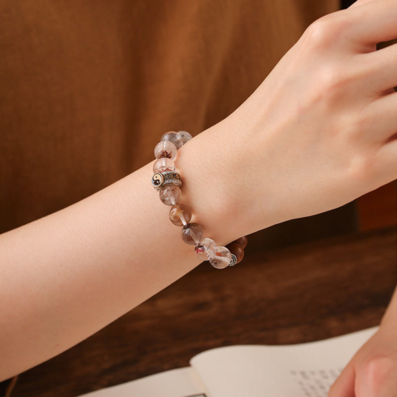 Lightning Struck Wood Red Phantom Bracelet – worn on wrist with translucent crystal beads, yin-yang charm, dark wood table...