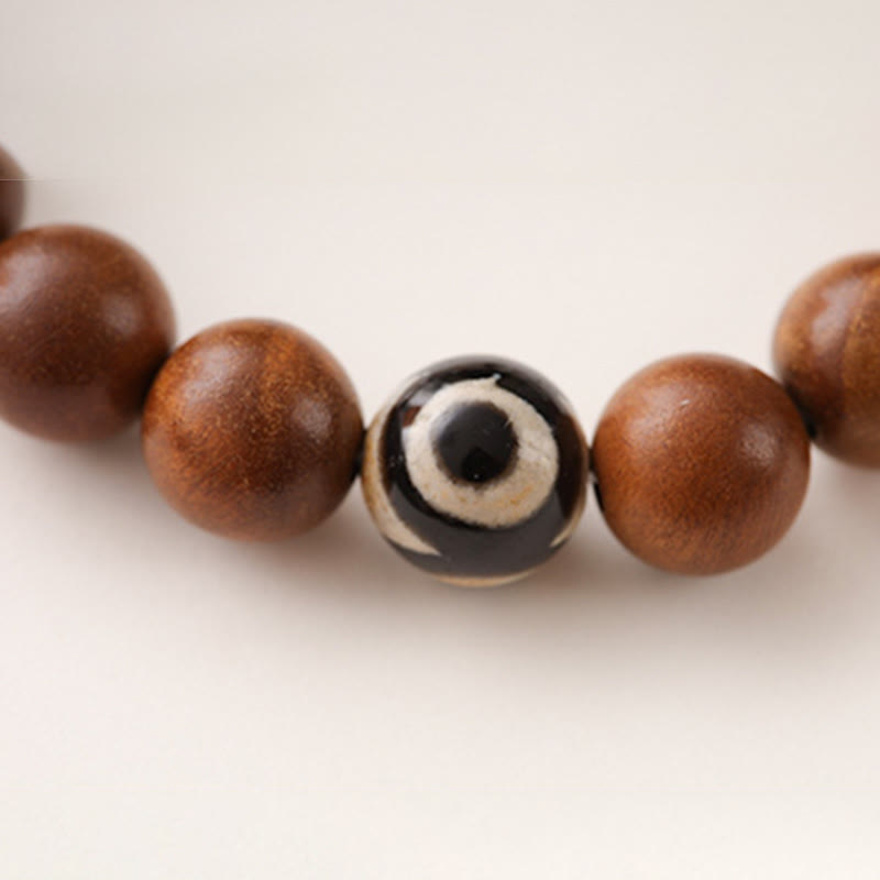 Lightning Struck Wood Red Phantom Bracelet – macro detail of three-eyed dzi bead accent with smooth brown wooden beads on ...