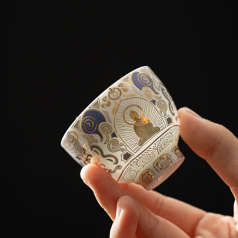 White Thangka Buddha Kung Fu Tea Cup – hand-held side view showing gold Buddha and blue clouds on white ceramic, closeup detail