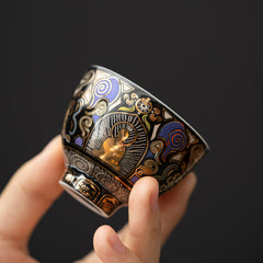 Black Thangka Buddha Kung Fu Tea Cup – hand-held side view showing gold Buddha and blue cloud motifs on black ceramic, closeup detail