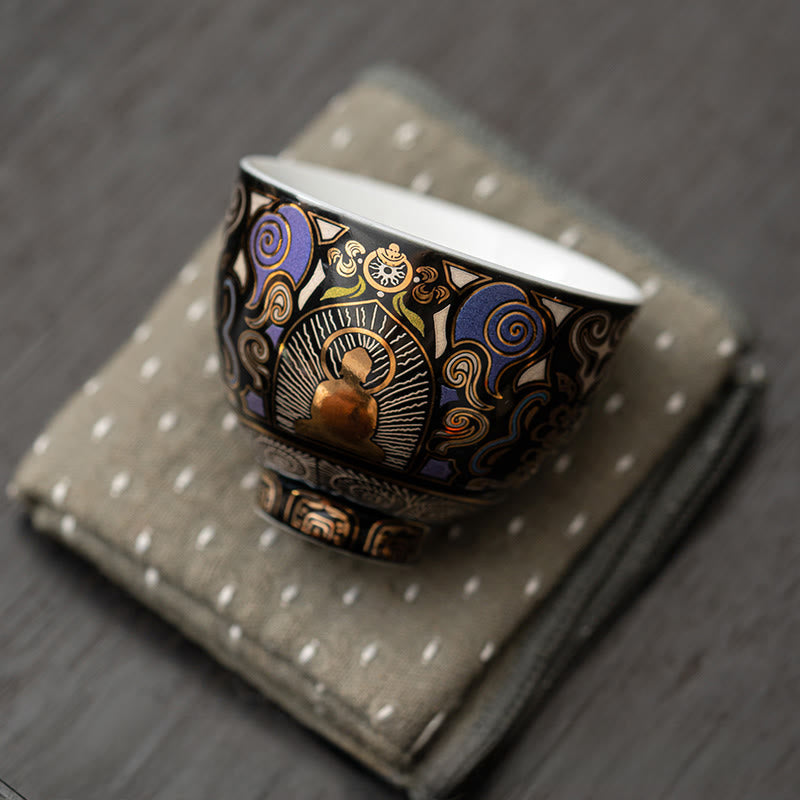 Black Thangka Buddha Kung Fu Tea Cup – front view on grey dotted linen napkin, gold and blue Thangka motifs, elegant display