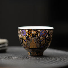 Black Thangka Buddha Kung Fu Tea Cup – front view on stone tea tray with blurred teaware background, zen tea setting