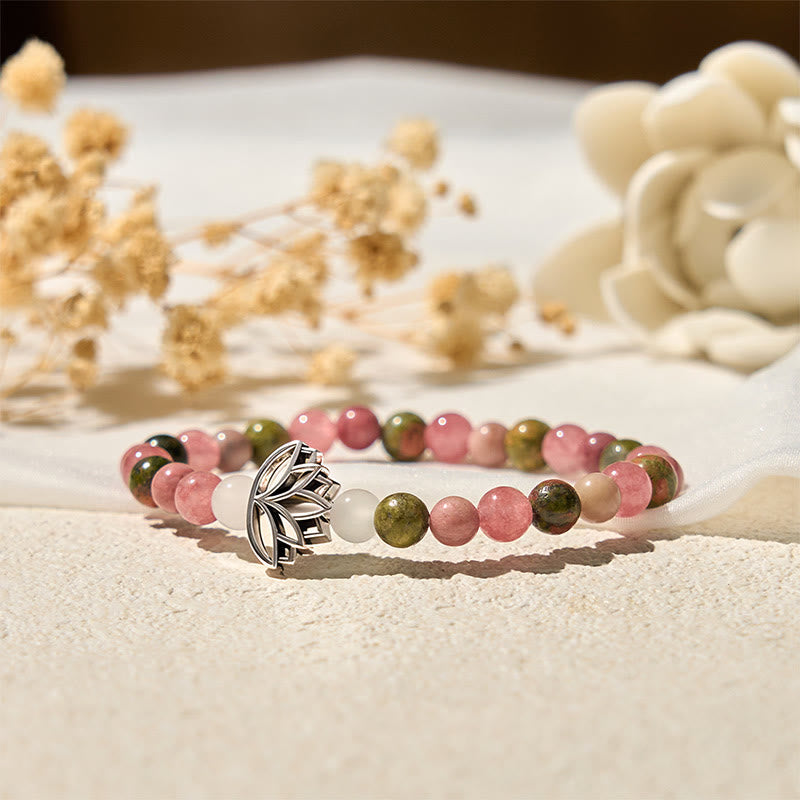 Silver lotus charm on pink and green gemstone stretch bracelet, close-up artisan crystal healing jewelry