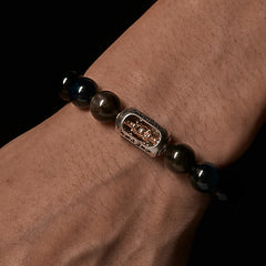 Silver Sheen Obsidian Bracelet worn on wrist - black background, two-tone silver gold charm with Buddha figure, mens protection jewelry