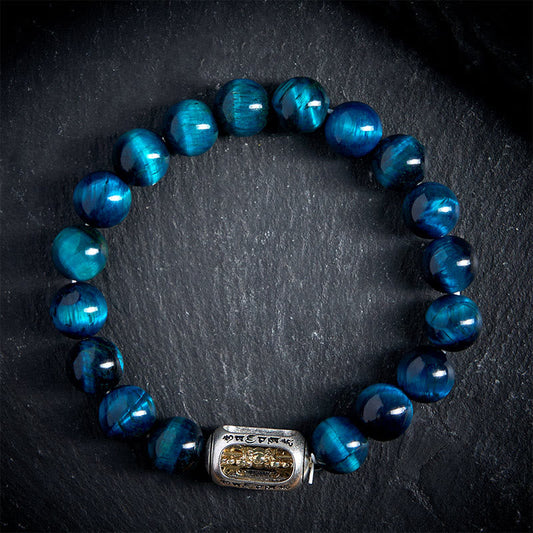 Blue Tiger Eye Bracelet - top-down view on dark stone, silver and gold mantra charm centerpiece, mens beaded healing jewelry