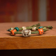 Tibetan Dragon Dice Bone Rope Bracelet – close-up carved dragon bead with orange dice on wood, Protection