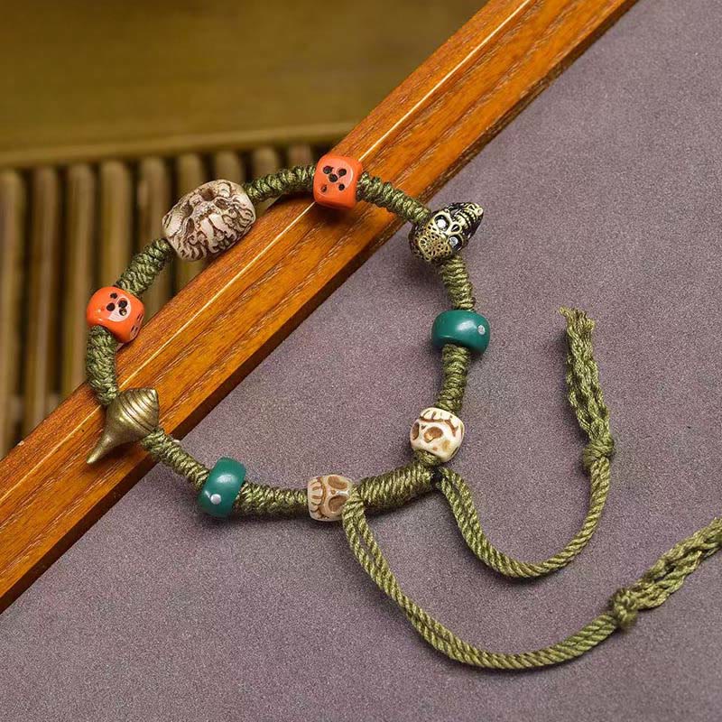 Tibetan Dragon Dice Bone Rope Bracelet – diagonal view with orange dice and ivory beads on mauve, Artisan