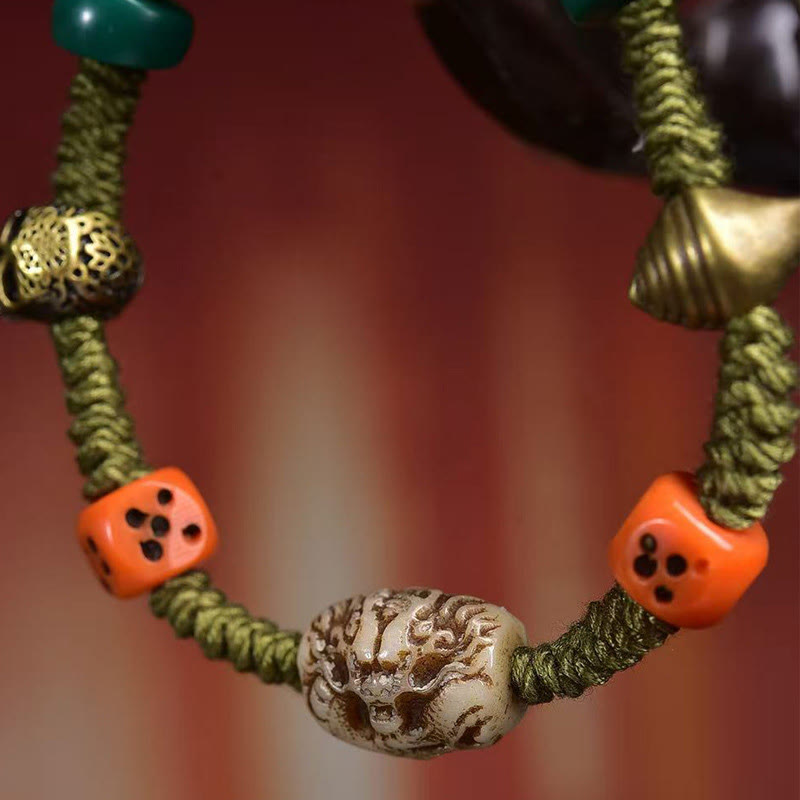Tibetan Dragon Dice Bone Rope Bracelet – macro skull bead flanked by orange dice and teal accents, Strength
