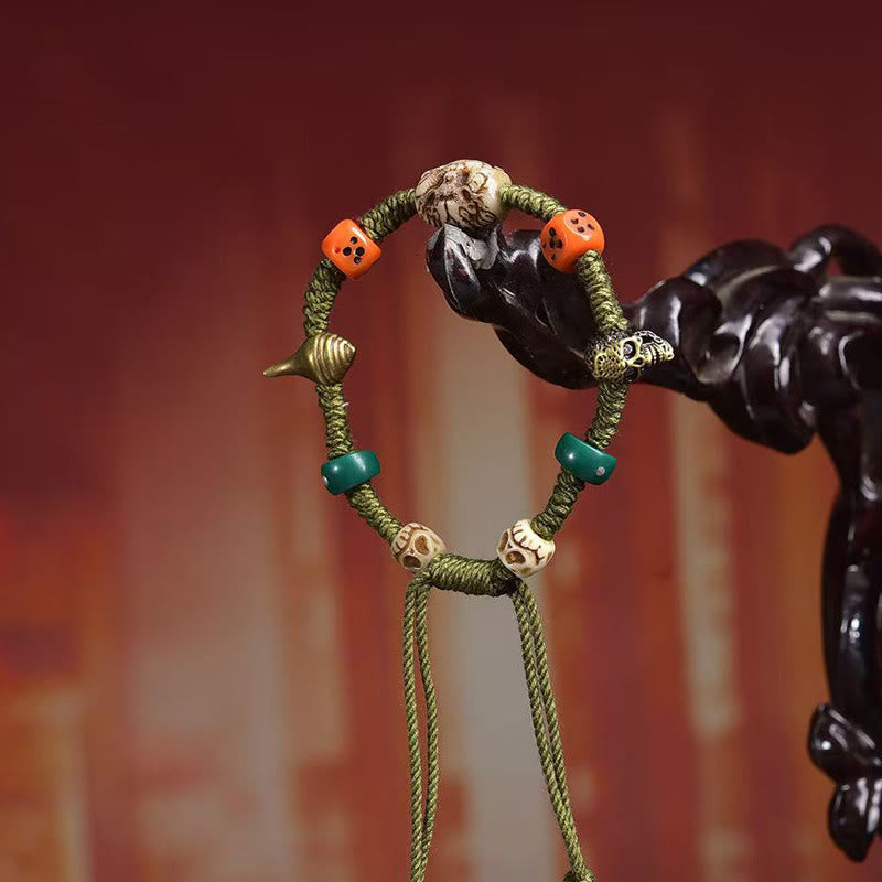 Tibetan Dragon Dice Bone Rope Bracelet – on carved black stand against warm amber bokeh, Spiritual