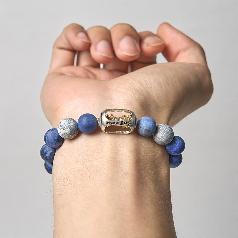 Sodalite Grey Jasper Om Bracelet – on wrist, light background, blue sodalite beads with engraved center, mens bead bracelet