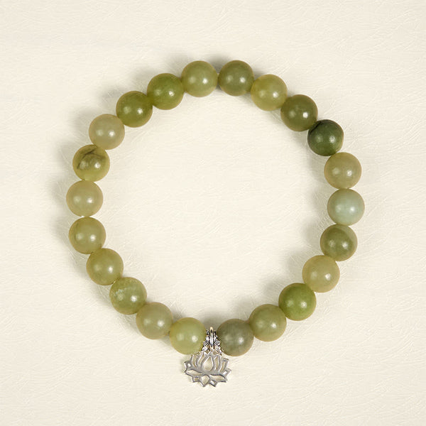 Natural Cyan Jade Bracelet flat lay with silver lotus pendant, healing gemstone
