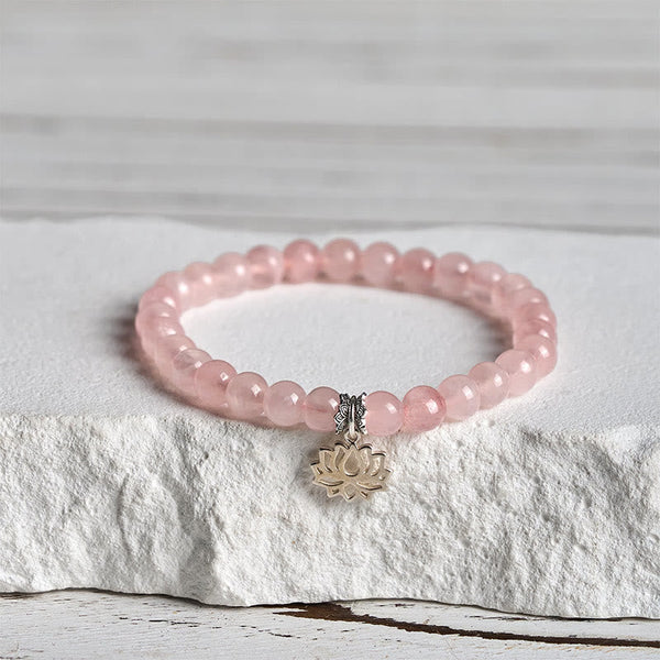Pink Lotus Bracelet close-up on textured pedestal, silver charm rose quartz