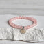 Pink Lotus Bracelet close-up on textured pedestal, silver charm rose quartz