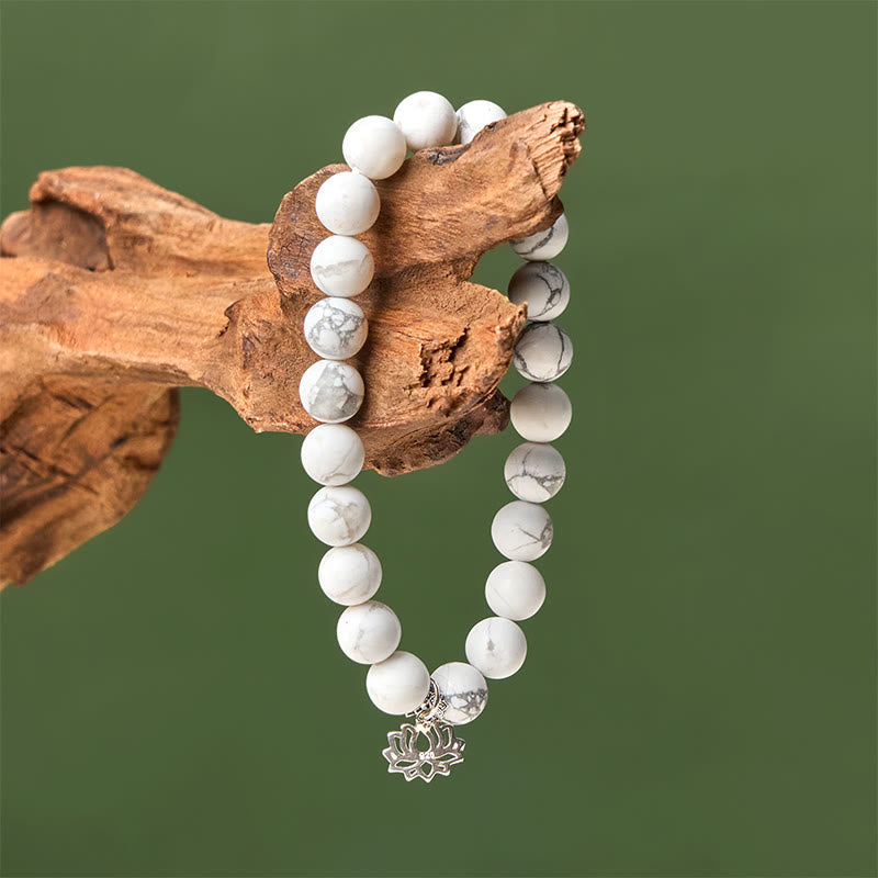 White Turquoise Lotus Bracelet – hanging on weathered wood, vertical drape showing silver lotus, white turquoise beads