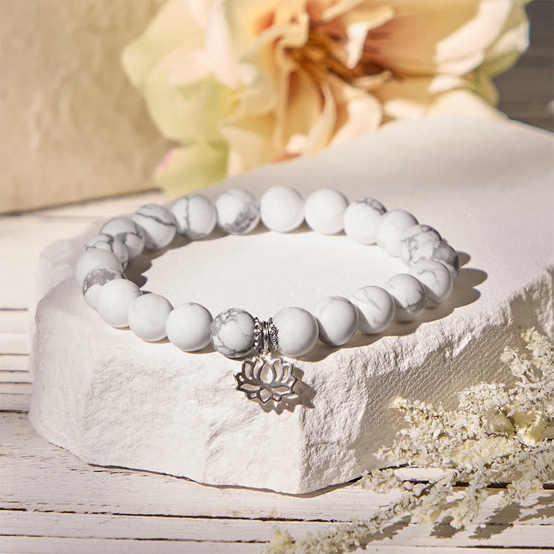 White Turquoise Lotus Bracelet – on stone block with dried flowers, warm sunlight on silver lotus charm, turquoise bracelet