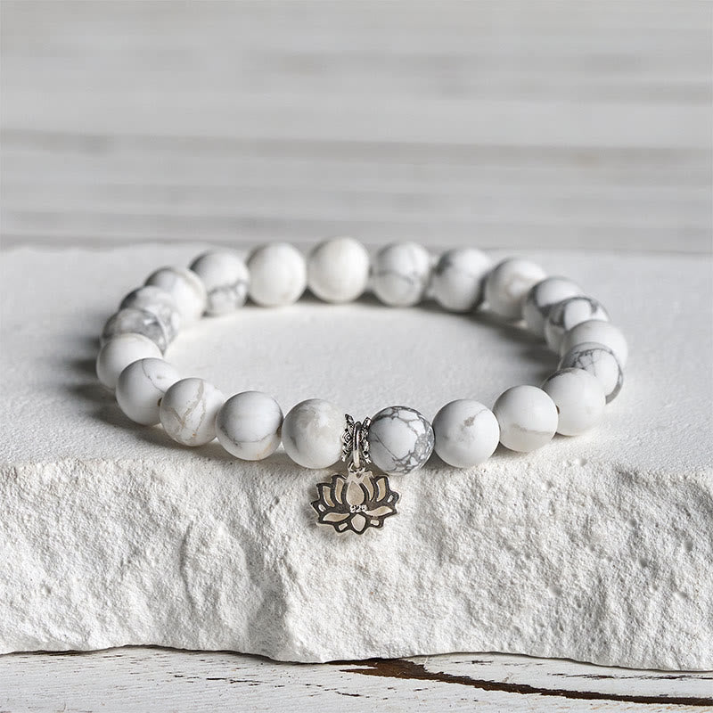 White Turquoise Lotus Bracelet – angled view on rough stone, silver lotus charm and grey-veined beads, turquoise bracelet