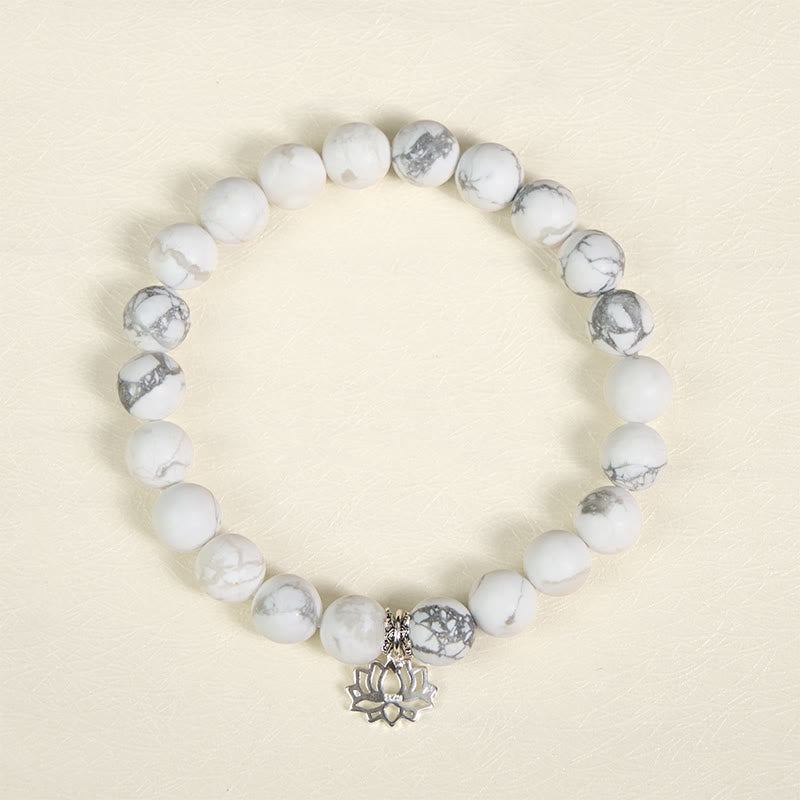 White Turquoise Lotus Bracelet – top-down flat lay on warm cream, oxidized silver lotus charm, natural white turquoise