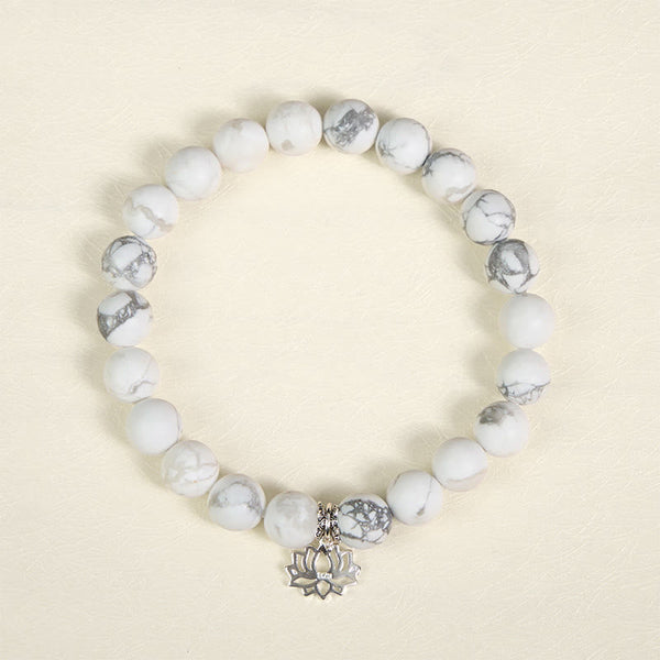White Turquoise Lotus Bracelet – top-down flat lay on warm cream, oxidized silver lotus charm, natural white turquoise