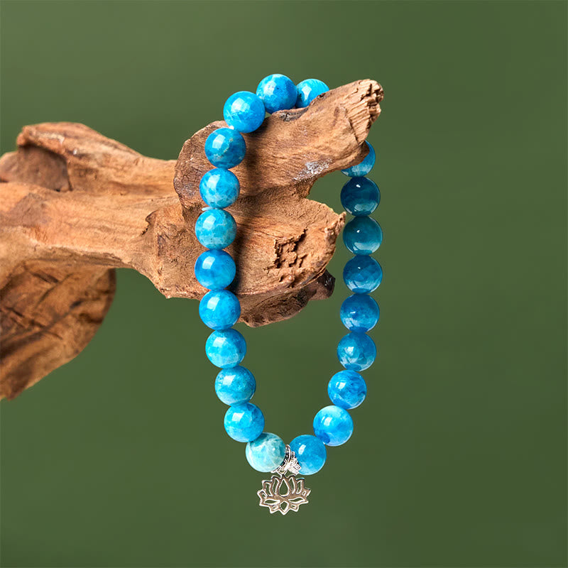 Apatite Lotus Silver Bracelet – draped on driftwood, blue apatite beads against sage green, silver lotus pendant