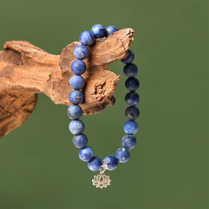 Sodalite Lotus Bracelet – draped on natural driftwood against sage green, blue stone beaded bracelet