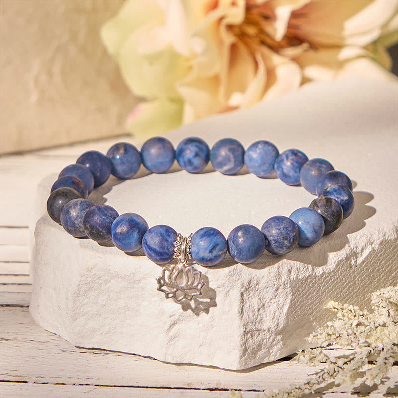 Sodalite Lotus Bracelet – blue beaded bracelet on white stone pedestal with dried flowers, sodalite healing jewelry