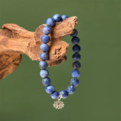 Sodalite Lotus Bracelet – draped on natural driftwood against sage green, blue stone beaded bracelet