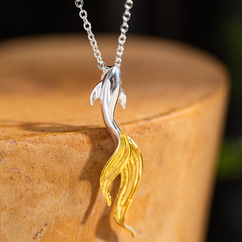 Silver Golden Koi Fish Luck Necklace – macro three-quarter view of leaping koi on polished wooden stump