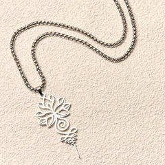 Lotus Unalome Chakra Necklace – Silver lotus pendant flat-laid on textured cream, mindfulness jewelry