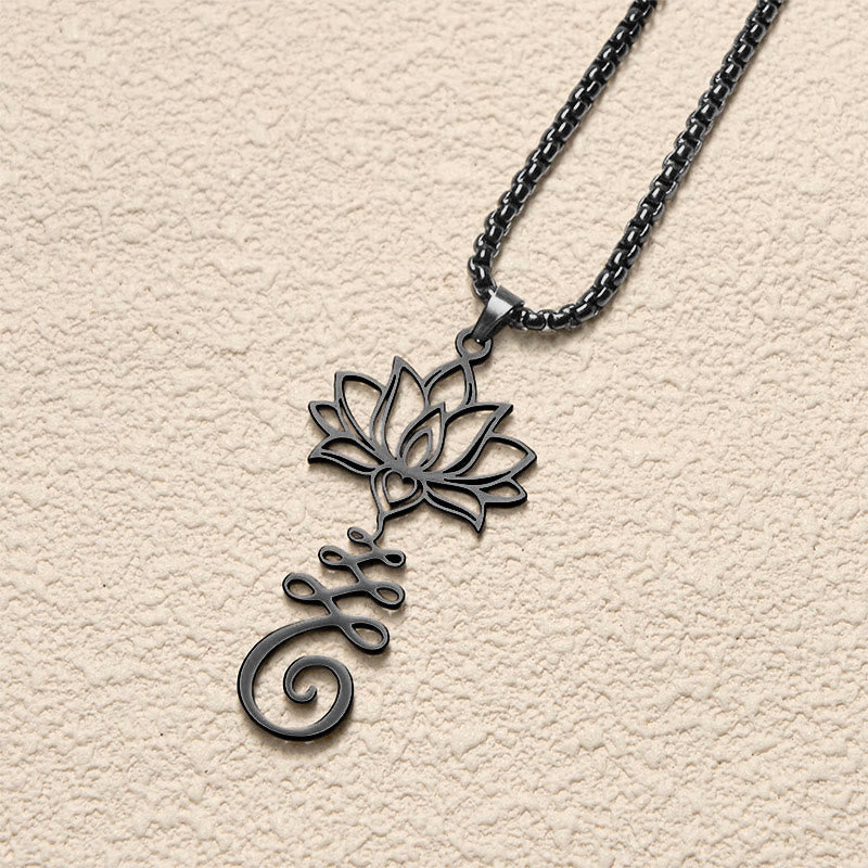 Chakra Lotus Necklace – Black lotus-unalome pendant at angled view on cream surface, enlightenment pendant